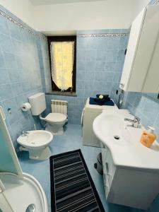 een blauw betegelde badkamer met 2 wastafels en een toilet bij La maison de Daniela in Settimo Vittone