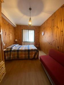 1 dormitorio con 1 cama y 1 sofá rojo en Casa da Roberto en Roccaraso