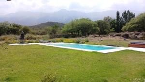 a swimming pool in a yard with mountains in the background at Cabaña romántica en la sierra in Yacanto