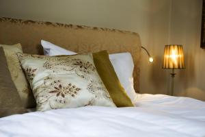 un letto con lenzuola bianche e cuscini con lampada di Sockerslottet Hotell a Kristinehamn