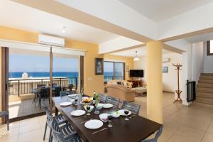 a dining room and living room with a view of the ocean at Villa Serena in Pomos