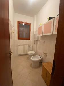 bagno con servizi igienici bianchi e finestra di Casa da Roberto a Roccaraso