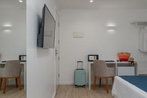 a bedroom with a bed and a table with chairs and a suitcase at Hotel Praia Bonita Jangadeiros Pajuçara in Maceió