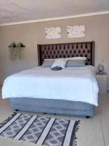 um quarto com uma cama grande e uma grande cabeceira. em Precious Estates Pearls em Zeerust