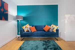 Station Apartment High Wycombe في هاي وايكومب: أريكة زرقاء في غرفة المعيشة بجدار أزرق