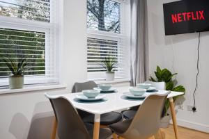 Station Apartment High Wycombe في هاي وايكومب: غرفة طعام بيضاء مع طاولة بيضاء وكراسي