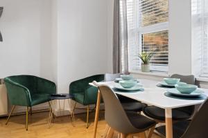 a dining room with a white table and green chairs at Station Apartment High Wycombe in High Wycombe
