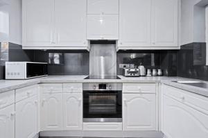 cocina con armarios blancos y fogones en Station Apartment High Wycombe, en High Wycombe