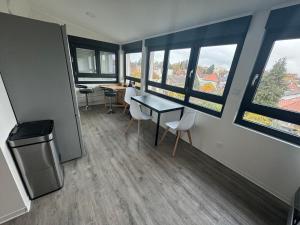 Habitación con mesa, sillas y ventanas. en # Le 13 # Nouveau T3 rénové au calme vue sur les Vosges, en Riedisheim