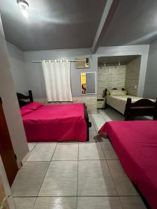 duas camas num quarto com lençóis cor-de-rosa em Casinha Vilarejo em Cabo Frio