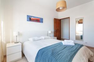 a white bedroom with a bed with a blue blanket at Spacious & Sunny Flat - Loulé in Loulé