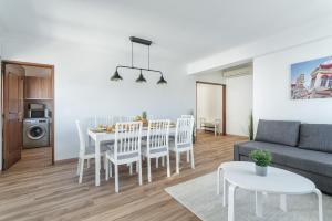 ein Wohnzimmer mit einem Tisch, Stühlen und einem Sofa in der Unterkunft Spacious & Sunny Flat - Loulé in Loulé