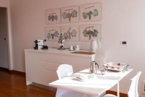 a white kitchen with a table and white chairs at Casa Gallinotto in Alba