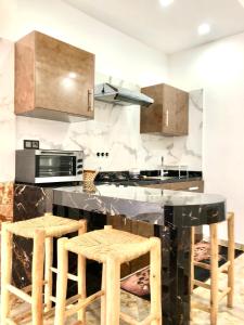 a kitchen with a black counter top and wooden stools at Padova Surf House in Imsouane