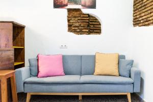 a blue couch with two colorful pillows on it at La casa del Sacristán. in Granada