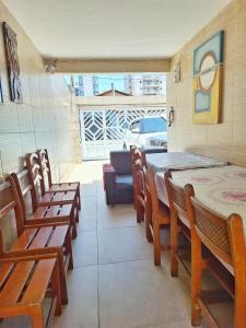 a dining room with wooden chairs and a table and a couch at Casa Praia Grande WIFI 2dorm 2ban 2carr churrasq 400mts da praia Tupi in Praia Grande