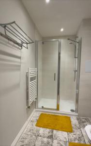 a bathroom with a shower and a yellow rug at Uxbridge Apartment in Uxbridge