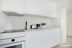 a white kitchen with white cabinets and a sink at Residence Madame Ponthieu in Paris