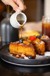 a person drizzling syrup onto a plate of food at ARTE HOTEL Lima in Lima