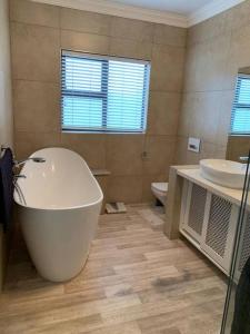 ein Badezimmer mit einer Badewanne, einem Waschbecken und einem WC in der Unterkunft Fairways Villa @ Bunker Close in Walvis Bay