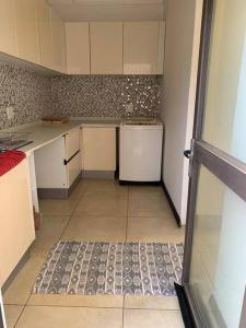 a small kitchen with a refrigerator and a tile floor at Fairways Villa @ Bunker Close in Walvis Bay