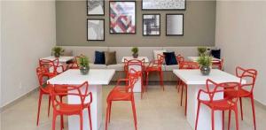 uma sala de jantar com mesas brancas e cadeiras vermelhas em Admirável Apartamento Em Frente Ao Metrô Brás ! Ap 56 A Torre 2 em São Paulo