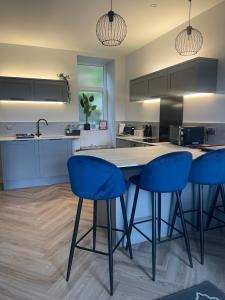 a kitchen with blue bar stools and a counter at Springlea in Oban