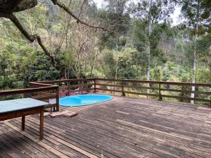 eine Holzterrasse mit einem Pool in der Mitte in der Unterkunft Cabana Fenix Sitio Nossa Terra in Joanópolis