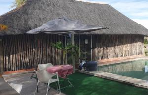 um guarda-sol e cadeiras junto a uma piscina em Paradise Camp delux Rooms em Grootfontein