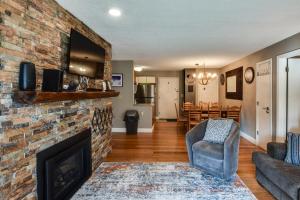 a living room with a brick fireplace and a chair at Ski-In and Out and Golf Condo with A and C at Holiday Valley! in Ellicottville