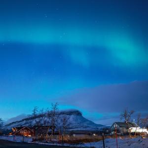une montagne enneigée la nuit avec une maison dans l'établissement Aurora View Lapland, Sky View Bedroom & Jacuzzi, à Kilpisjärvi