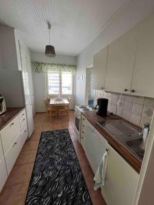 a kitchen with white cabinets and a black and white rug at Majoitusta 4:lle Pori in Pori
