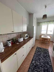 a kitchen with white cabinets and a table with a microwave at Majoitusta 4:lle Pori in Pori
