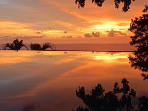 una piscina con una puesta de sol en el fondo en Vista Naranja Ocean View House, en Mal País
