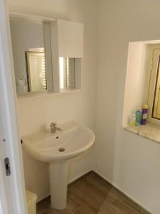 ein weißes Badezimmer mit einem Waschbecken und einem Spiegel in der Unterkunft The most beautiful view of Mussomeli in Mussomeli