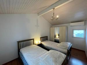 sypialnia z 2 łóżkami i żyrandolem w obiekcie Villa spacieuse avec jacuzzi, à 200m de la plage à Capbreton - FR-1-413-209 w mieście Capbreton