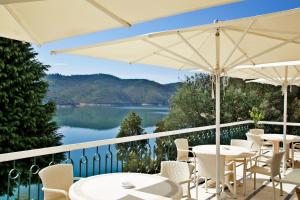 a balcony with tables and chairs and a view of a lake at Lago Azul Eco Hotel in Ferreira do Zêzere