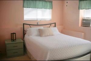 1 dormitorio con 1 cama con sábanas blancas y ventana en Komohana Hale LLC, en Kailua-Kona