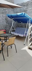 ein Bett und Stühle sowie ein Tisch und ein blauer Sonnenschirm in der Unterkunft Mini Loft in Iquique