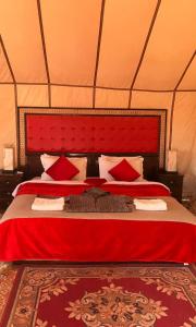 a bedroom with a red bed in a tent at Luxury Sahara Camp in Merzouga