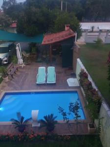 a swimming pool with two lawn chairs and a gazebo at Flats Casa Verde in Saquarema