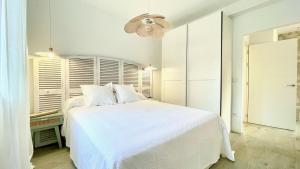 a white bedroom with a white bed and a chandelier at The Cliffs - VilaTurquesa A in Viveiro