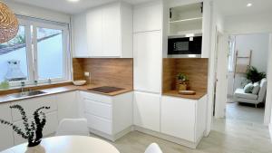 a kitchen with white cabinets and a table and a window at The Cliffs - VilaTurquesa A in Viveiro