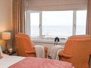 a bedroom with a bed and two chairs and a window at Sea View House in Hornsea