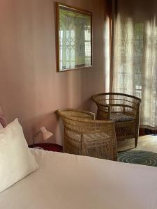 a bedroom with a bed and wicker chairs and a window at Central Garden Room Tamboerskloof in Cape Town