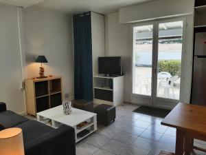 a living room with a couch and a tv at Villa Patio Charmante, 2 Pas des Plages, Terrasse, Parking, Piste Cyclable - FR-1-239-892 in Capbreton