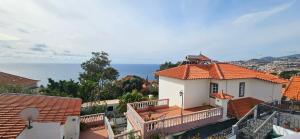 Biały dom z pomarańczowym dachem i oceanem w obiekcie Casa da Loba w Funchal