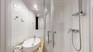 a white bathroom with a sink and a shower at APARTHOTEL TECTUM in Wrocław