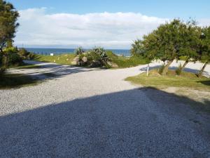 a gravel road with trees and the ocean in the background at Ili Ili Hotel Boutique in Mar del Plata