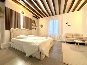 a bedroom with a white bed and a couch at Logement moderne avec jacuzzi in Aubervilliers